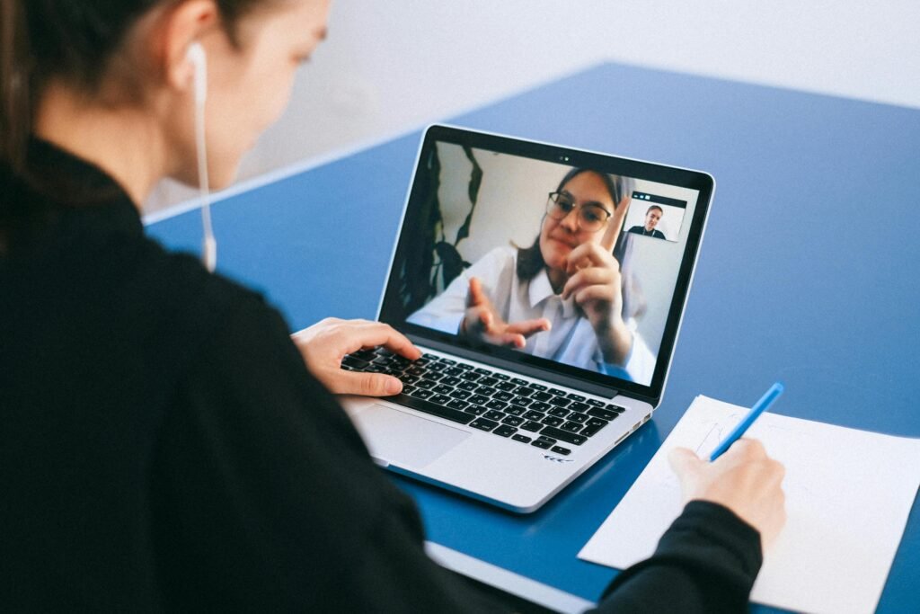 pexels-photo-4226256-4226256 Woman participating in a virtual meeting, taking notes during a video conference on a laptop.